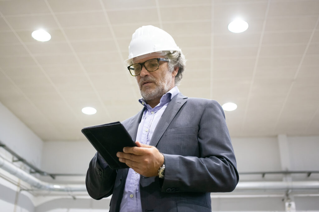 thoughtful man in protective helmet holding tablet